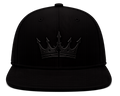 A black flat-brim baseball cap featuring a tonal black crown patch with a stylized crown emblem, shown against a plain white background.